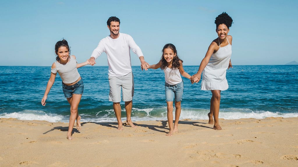 Family walking together on a tropical beach, representing stress-free packing and essential family travel gear for easy vacations.