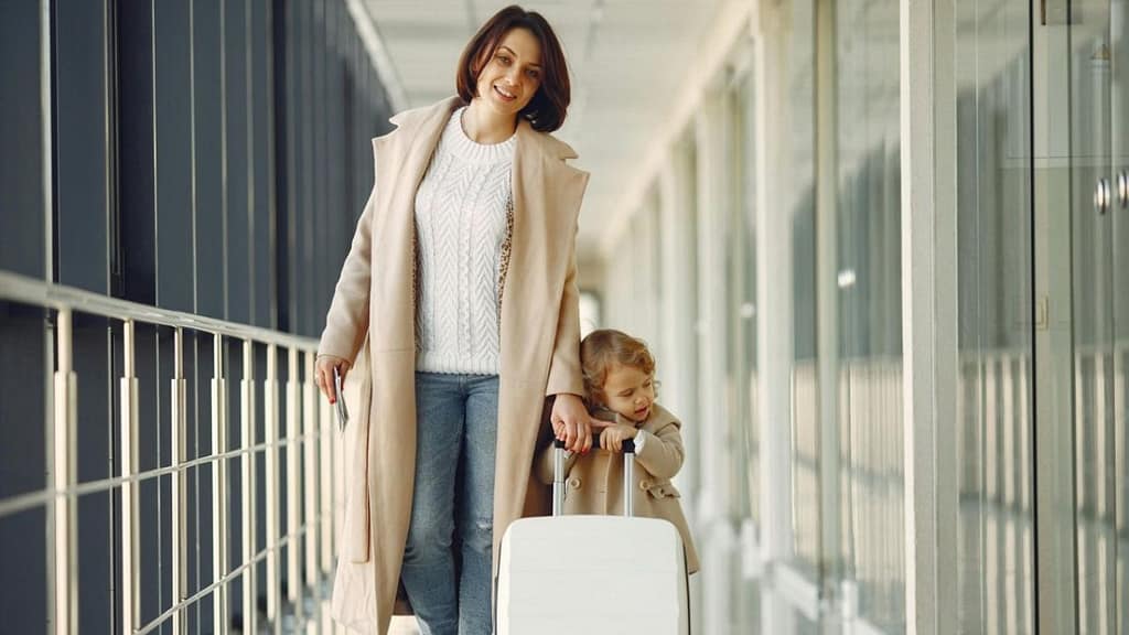 Mother walking through an airport with young child and suitcase, representing easier and stress-free family travel.