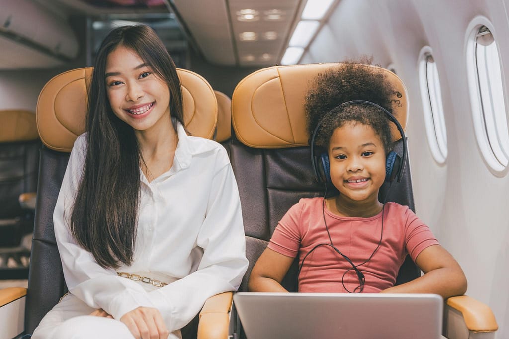 family-flying-with-kids-airplane-travel | Go With The Family family traveling on airplane with kids sitting together during flight
