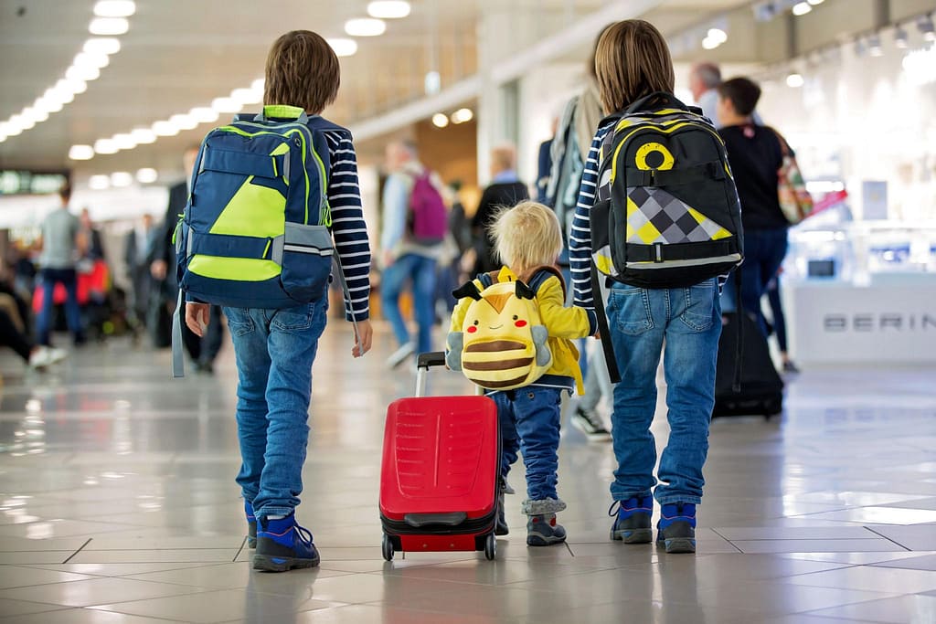 family-travel-airport-with-kids | Go With The Family family traveling through airport with kids and luggage
