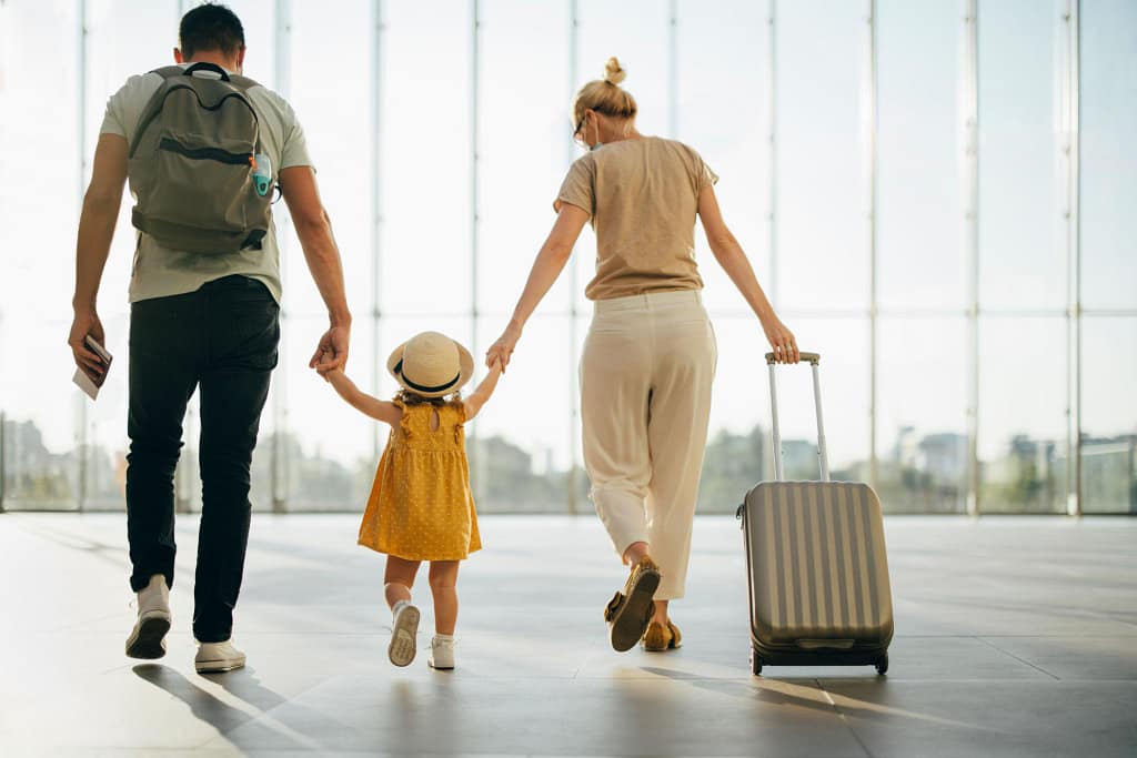 family traveling with kids at airport carrying luggage and travel gear