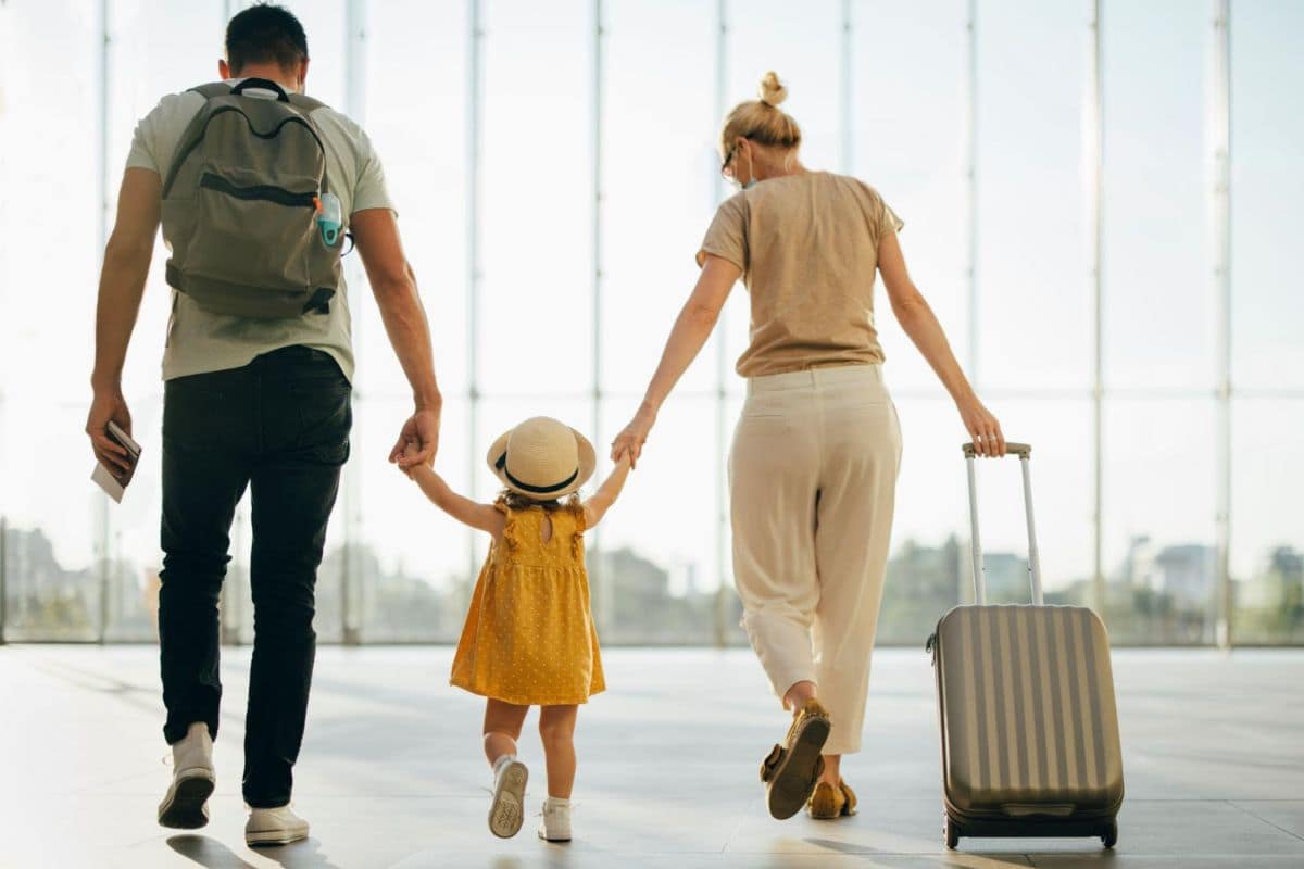 How to Make Family Travel Easier, More Fun, and More Affordable | Go With The Family Family walking through an airport with luggage, showing how family travel can be easier, more fun, and more affordable with good planning.