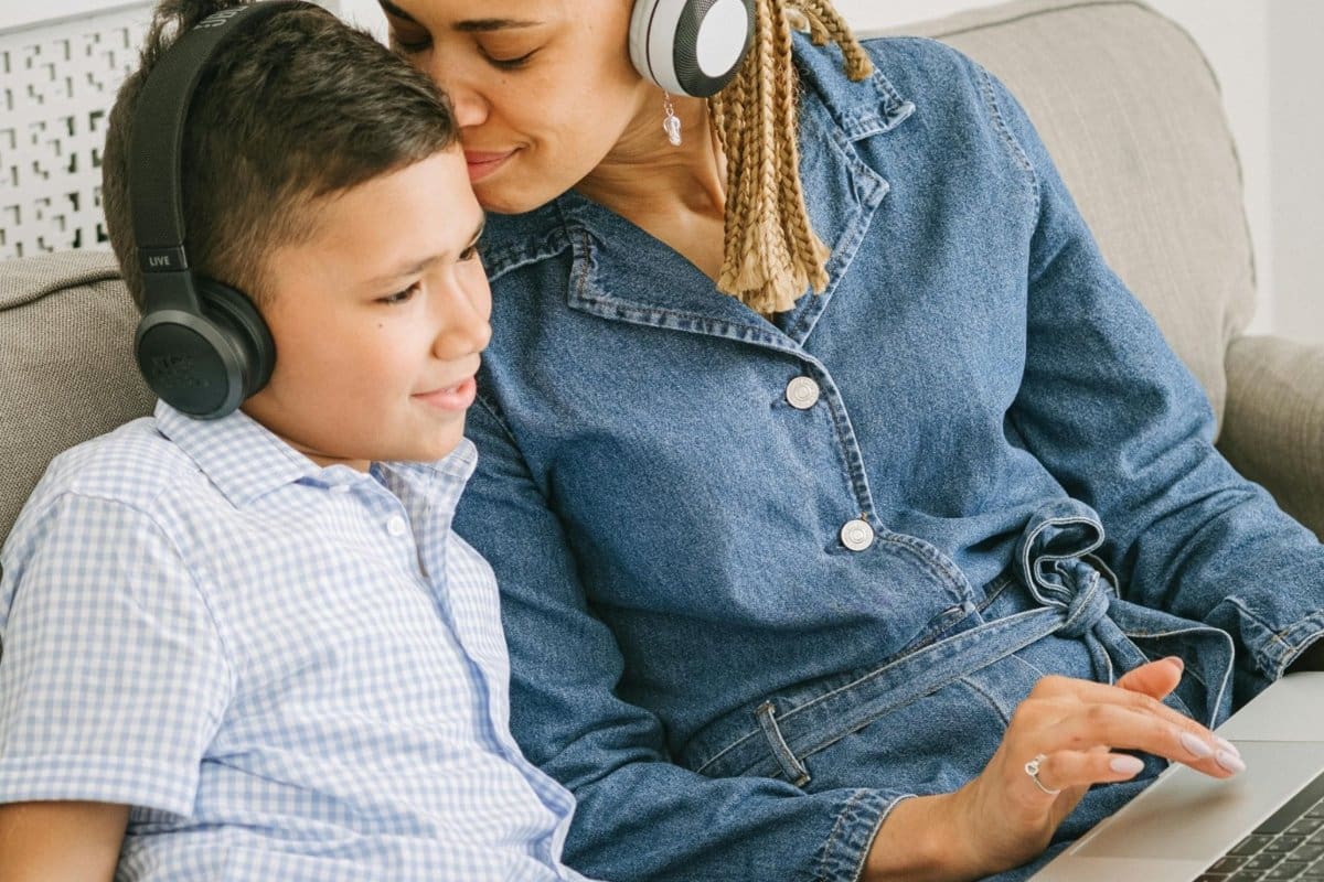kid-headphones-travel_1200x800 | Go With The Family Mother and child using kid-safe headphones together while looking at a laptop, ideal for travel entertainment.