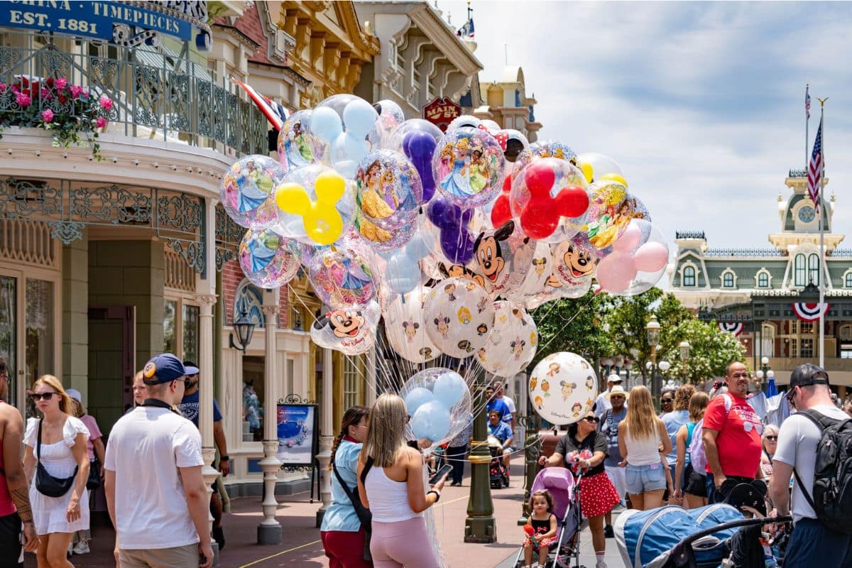 disney-world-main-street-family-balloons | Go With The Family Families walking along Main Street at Magic Kingdom with colorful Disney balloons.
