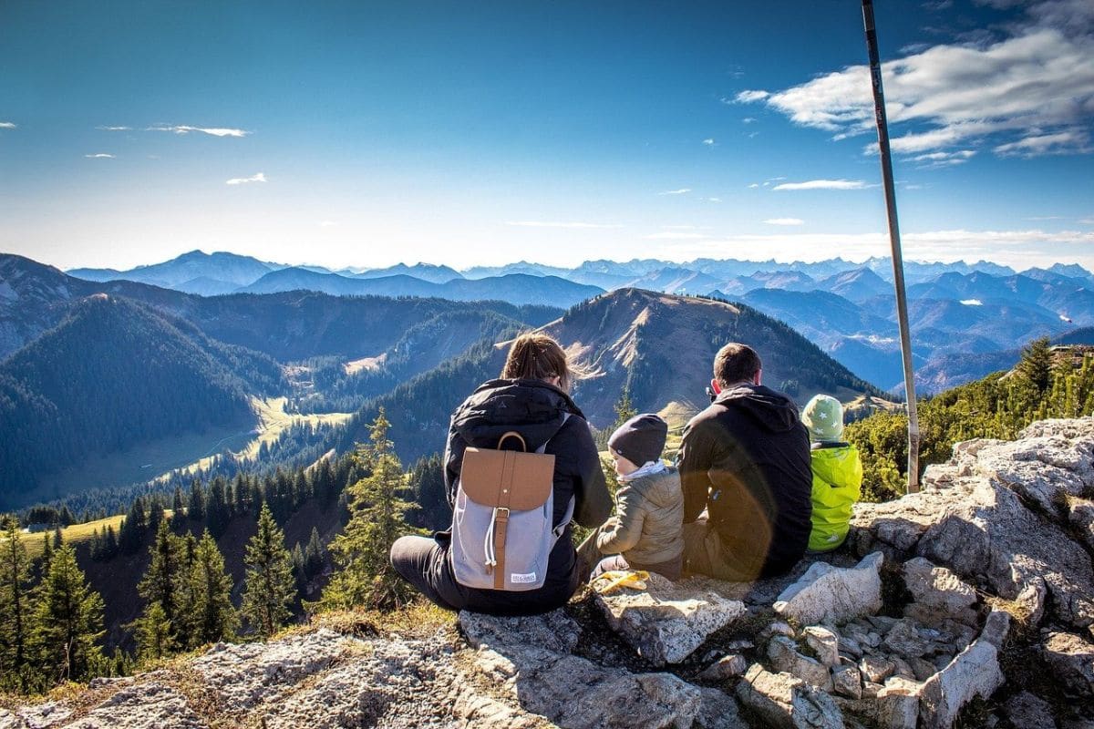 family-travel-inspiration | Go With The Family Family enjoying a scenic mountain viewpoint while planning their next travel adventure