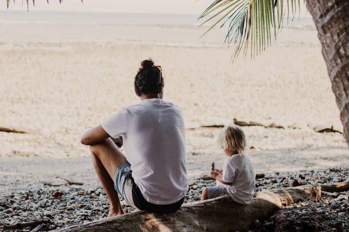 Family Enjoying a Beach Day in Costa Rica | Go With The Family Parent and young child relaxing together on a tropical beach in Costa Rica, enjoying a peaceful family beach vacation.