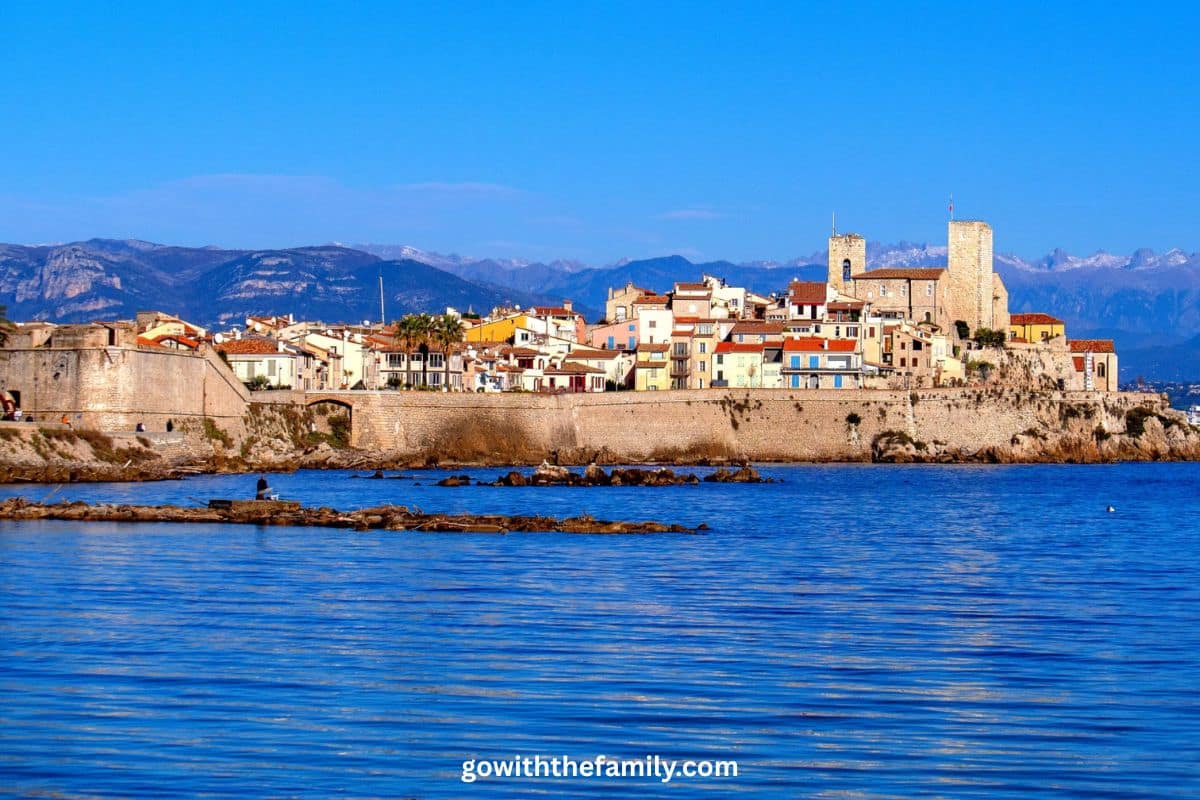 france-family-beach-destination-antibes-french-riviera | Go With The Family Antibes on the French Riviera with calm blue Mediterranean water and historic waterfront buildings