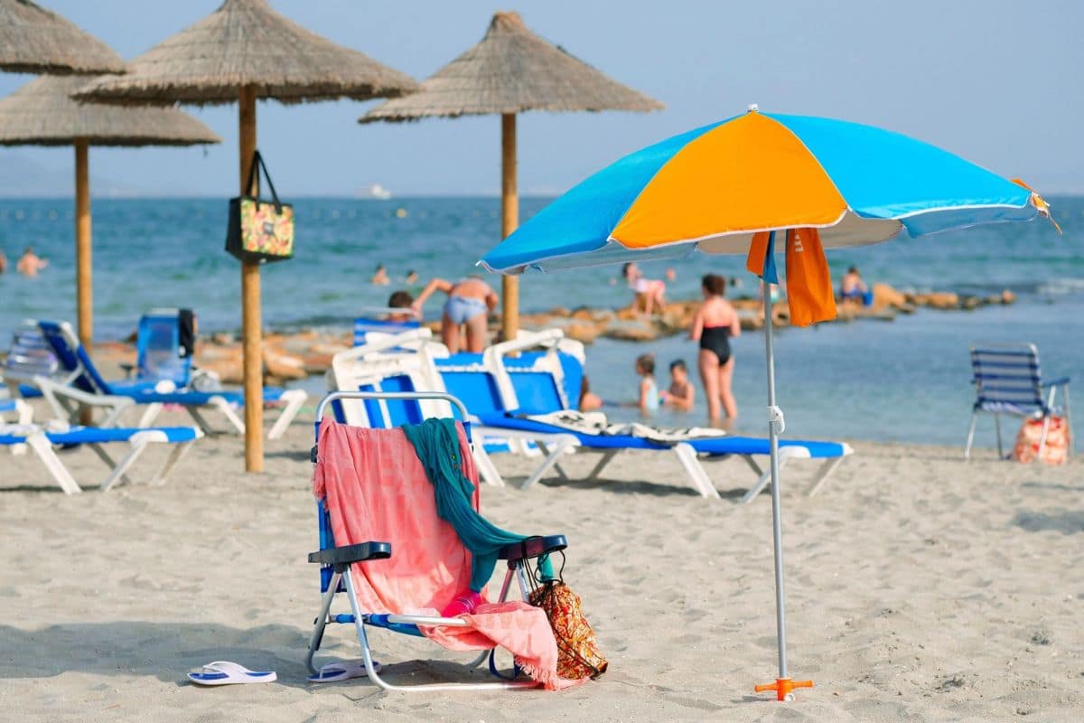 Beach Day in Los Alcázares, Spain | Go With The Family Colourful beach umbrella, chairs, and holidaymakers enjoying the beach in Los Alcázares, Spain.