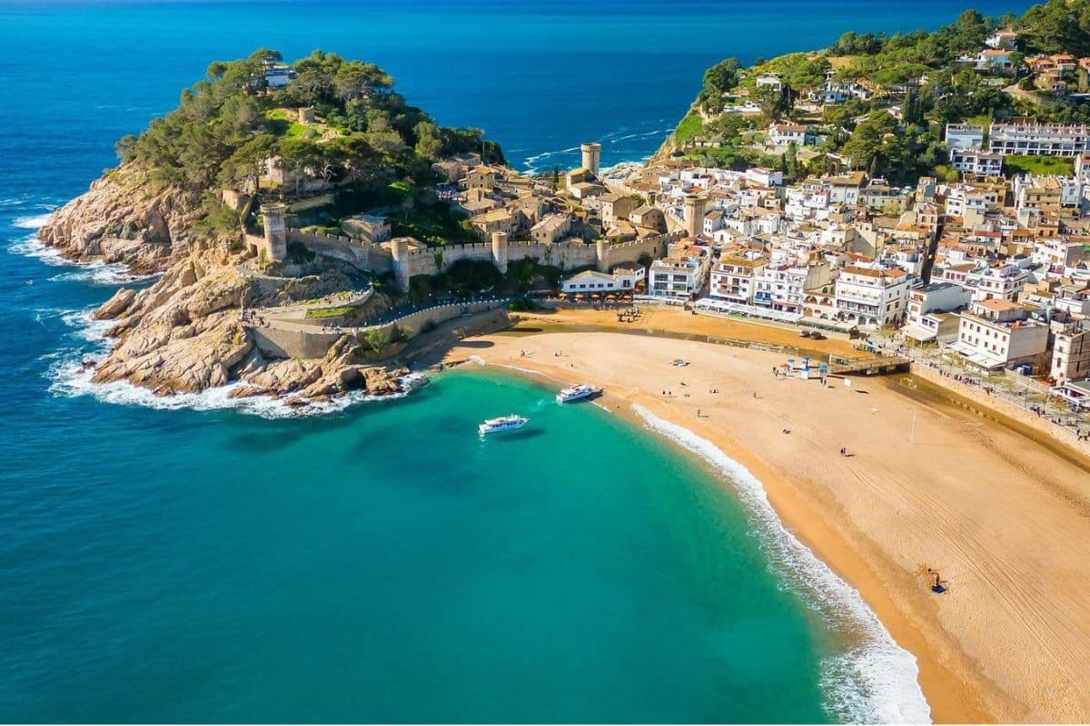 Costa Brava, Spain – Tossa de Mar Family Beach | Go With The Family AI-generated view of Tossa de Mar on Spain's Costa Brava, showing a sandy Mediterranean beach, turquoise water, and a historic hilltop castle.