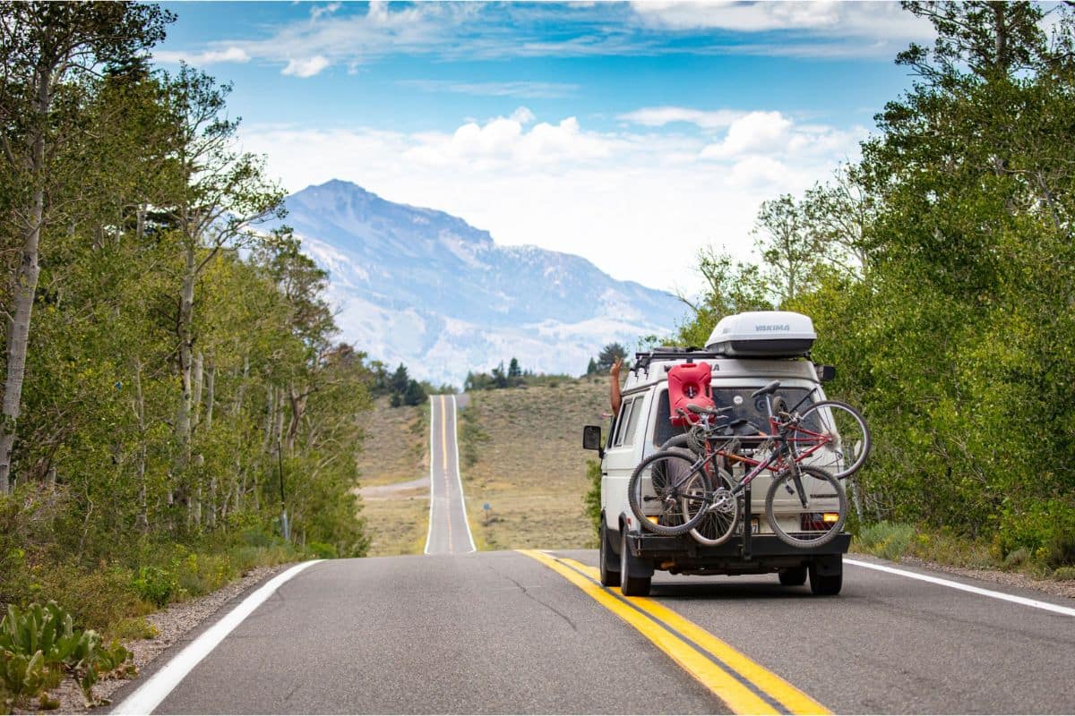 Best Family Road Trips in North America | Go With The Family Family road trip vehicle with bicycles driving along a scenic mountain highway in North America