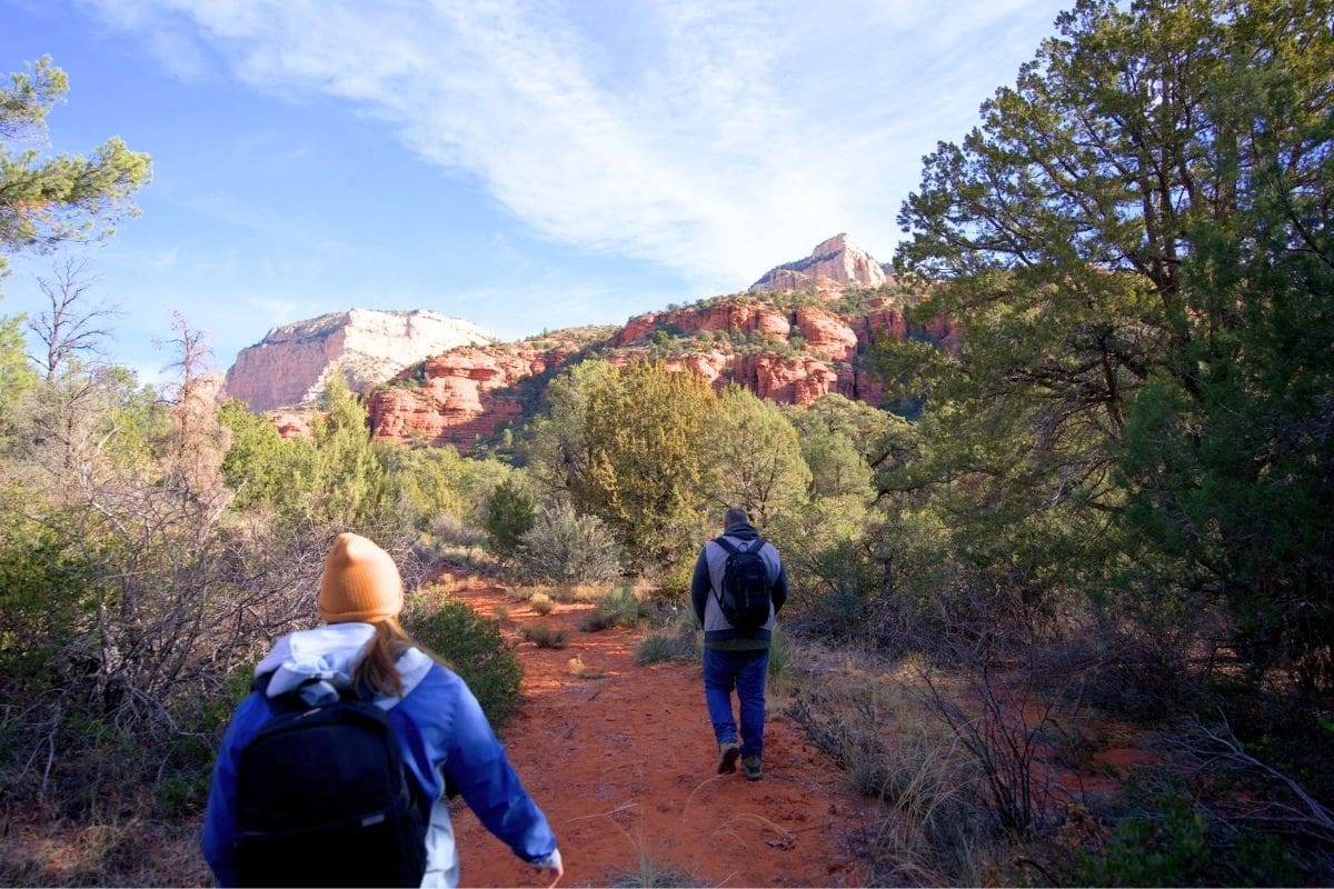 Hiking Through Sedona's Red-Rock Country | Go With The Family Hikers walking a red-rock trail through juniper country near Sedona, Arizona