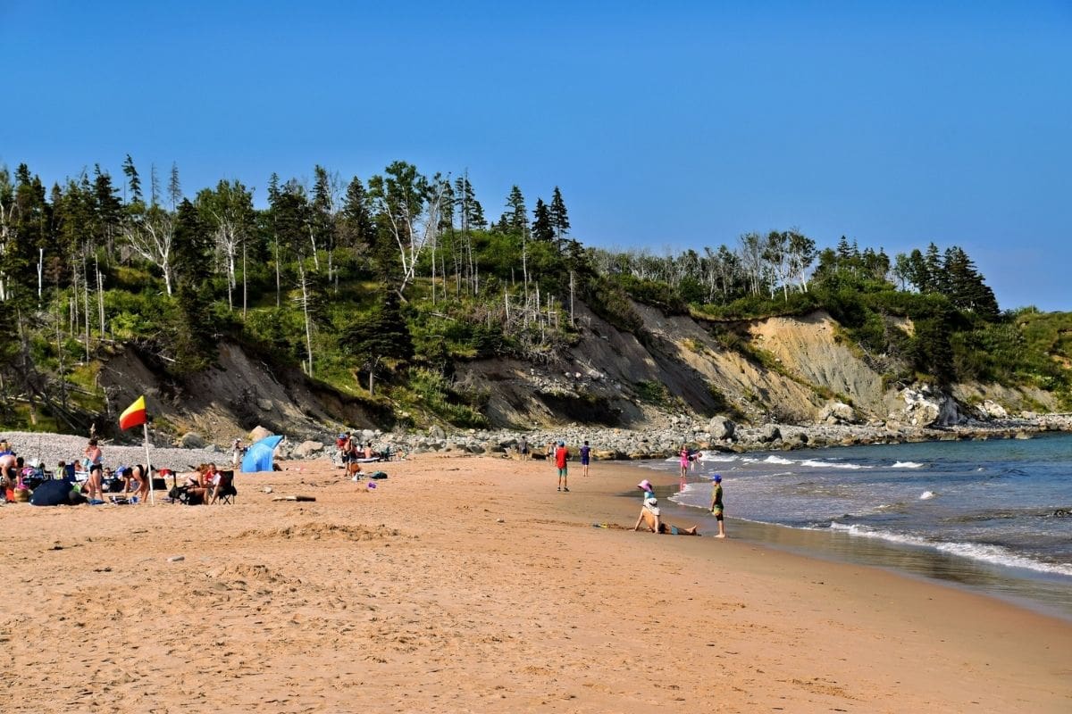 Ingonish Beach — Cape Breton Highlands National Park | Go With The Family Families enjoying Ingonish Beach beneath forested hills in Cape Breton Highlands National Park, Nova Scotia