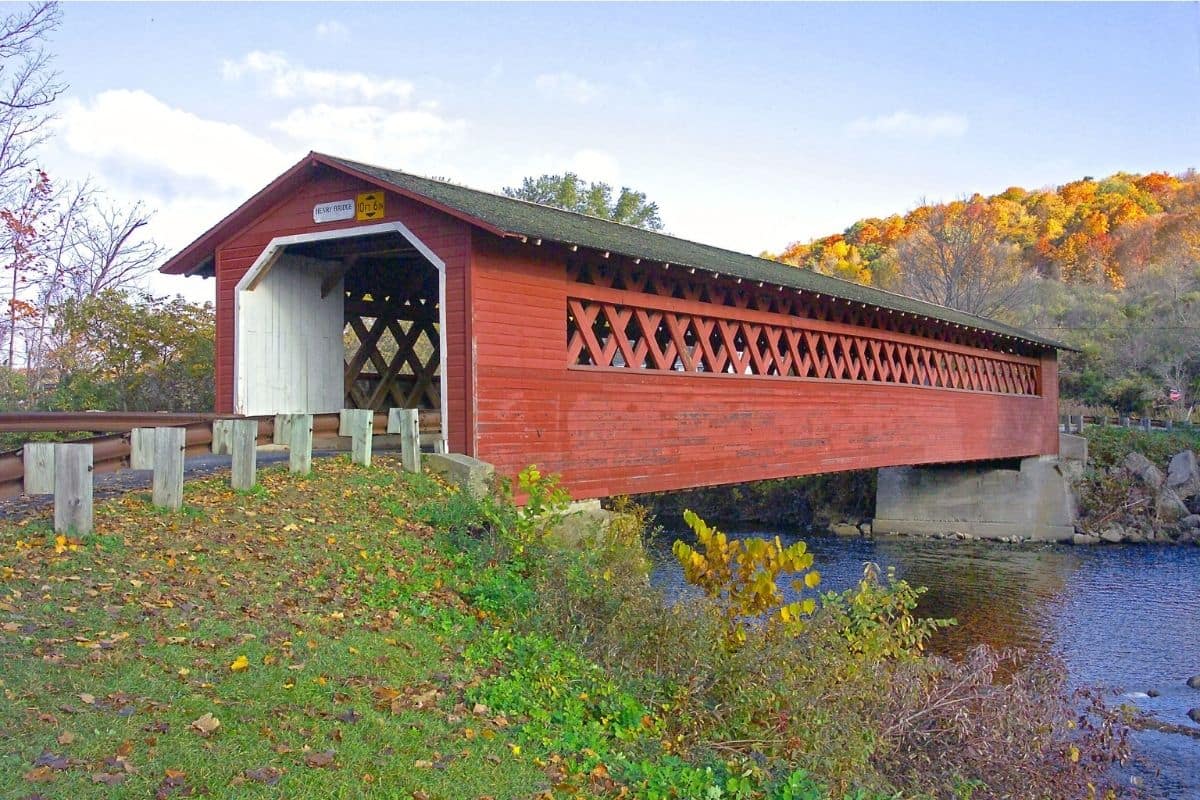 Vermont Covered Bridge in Autumn | Go With The Family Historic red covered bridge surrounded by autumn foliage in Vermont