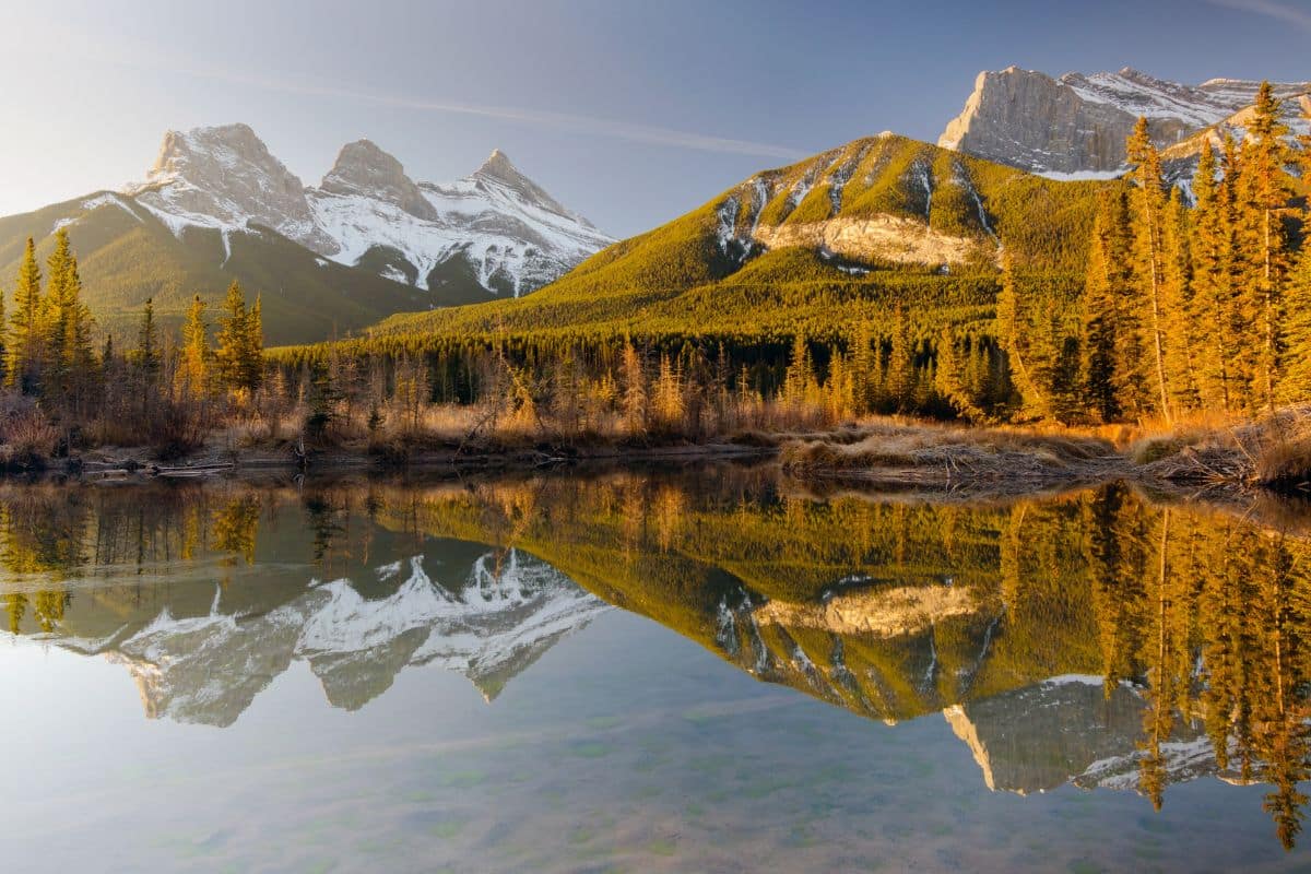 Three Sisters in Canmore | Go With The Family Three Sisters mountains reflected in calm water near Canmore in the Canadian Rockies, Alberta