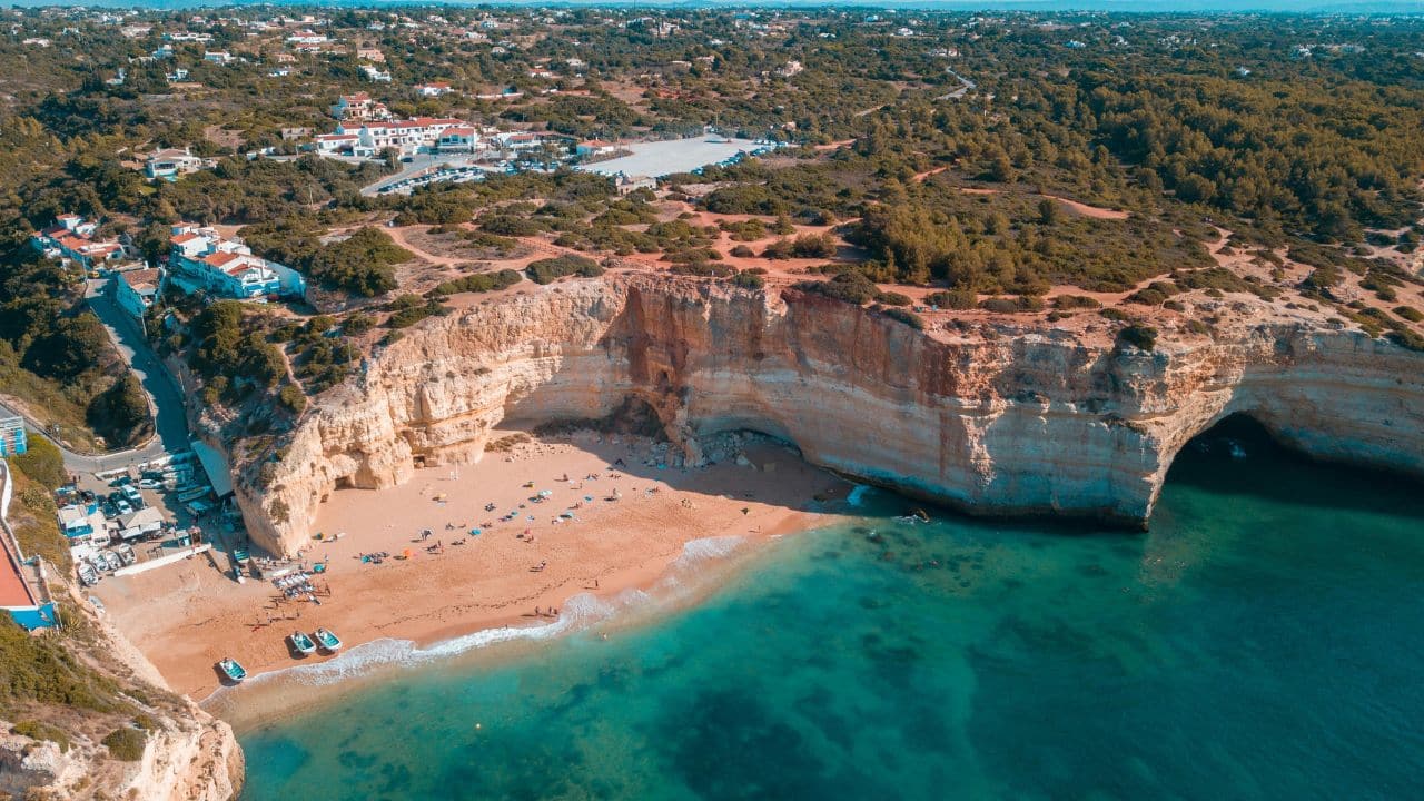 Praia da Marinha, Algarve Portugal – Family Beach Destination | Go With The Family Aerial view of Praia da Marinha in the Algarve, Portugal, with clear turquoise water and golden cliff coastline.